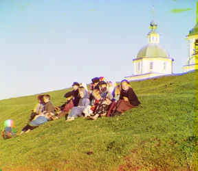 Niños rusos sentados al lado de una colina cerca de una iglesia y una torre de campana en el campo cerca del Lago Blanco, en el norte de Rusia europea, 1905-1915